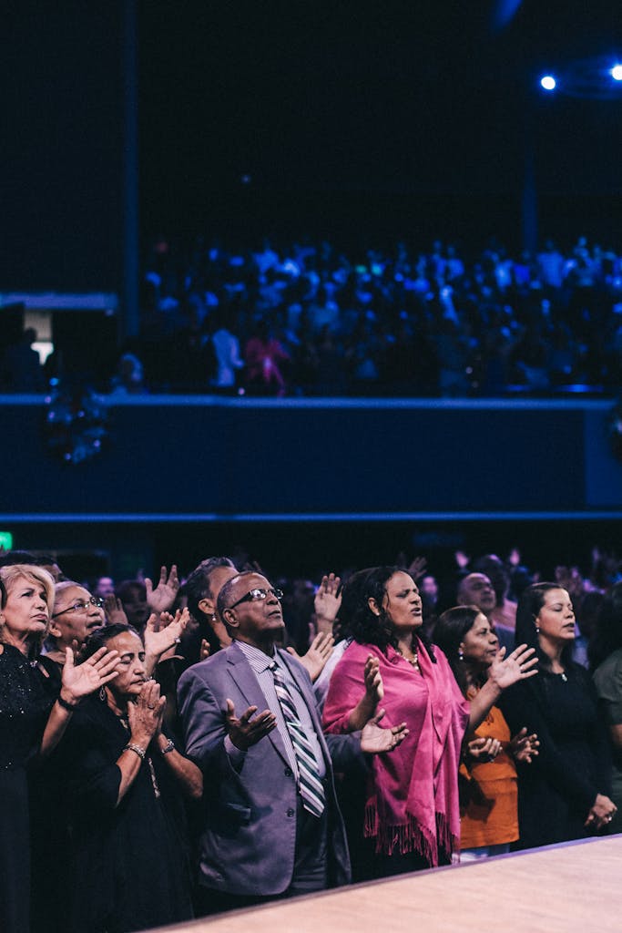 A diverse group of people participating in a lively worship event in a large auditorium.